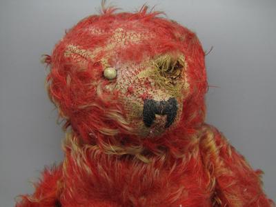 Very threadbare red teddy bear